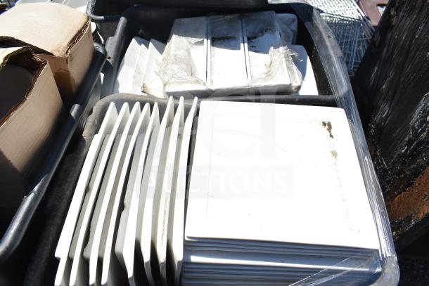 Pallet of assorted items featuring square white plates and bowls, stacked and wrapped, some visible wear.