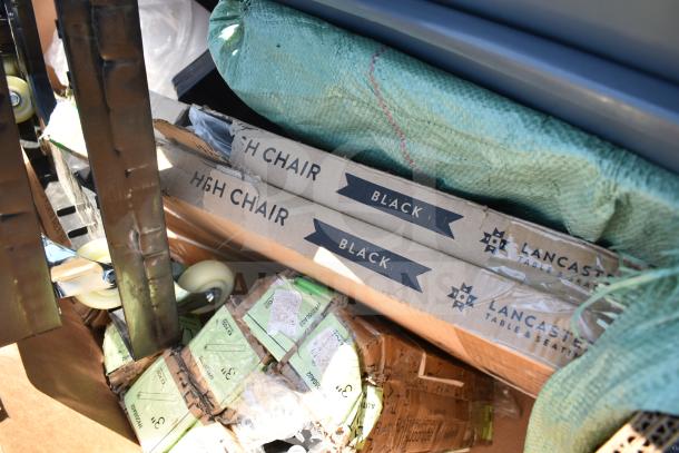 Boxes labeled "High Chair Black" and "Lancaster Table & Seating," surrounded by packing materials and wheels. Scratch and dent items.
