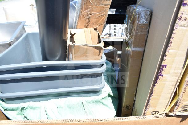 Box containing new scratch and dent items including a high chair, wall shelves, and trash cans, visible packaging and cardboard boxes.