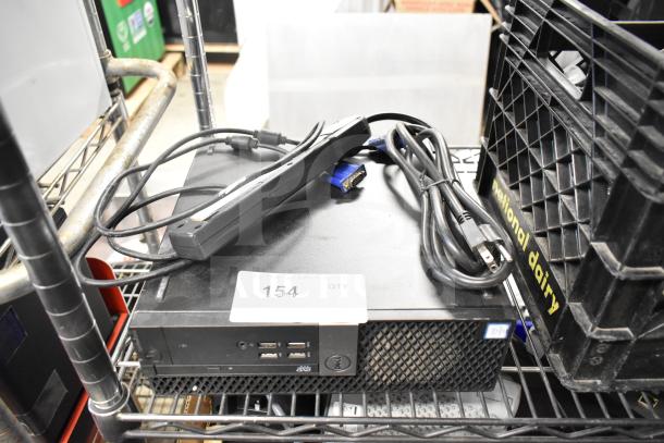 Dell computer tower with power cables on top. Front panel shows USB ports and DVD drive. Label marked "154" visible.