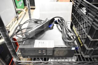 Dell computer tower with power cables on top. Front panel shows USB ports and DVD drive. Label marked "154" visible.