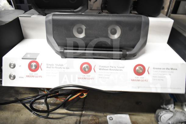 LG store display featuring XBoom Go speakers: P5, P7, P2. Shows control buttons and product features like battery life.