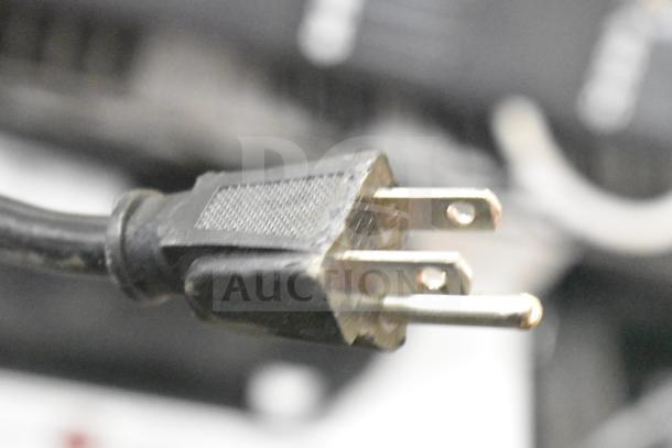 Close-up of a two-prong electrical plug for an LG Store Display with Speakers, highlighting the metal prongs and black housing.