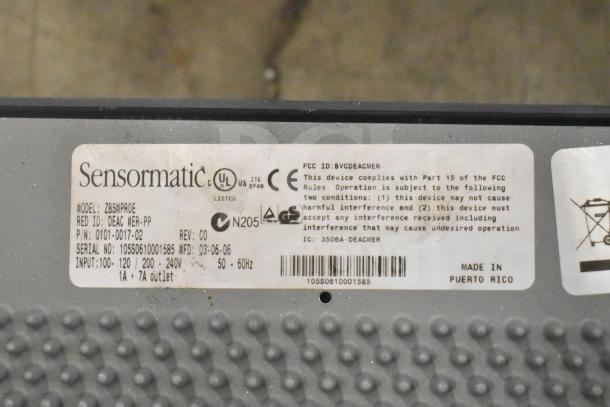 "Label on Sensormatic ZBSMPROE antenna deactivator, showing compliance details, input specs, and serial number."
