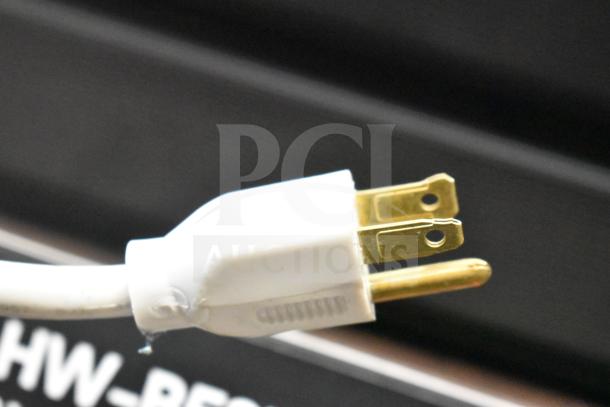 Close-up of a white power plug with brass prongs, part of Samsung Store Display with Sound Bar. Model "HW-RES...".