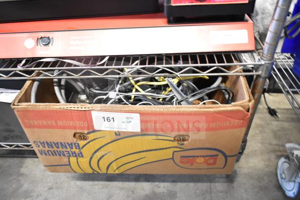 Lot of various items in a cardboard box, including cables and a Sensormatic ZBSTPSP-L. Box labeled "Premium Bananas."