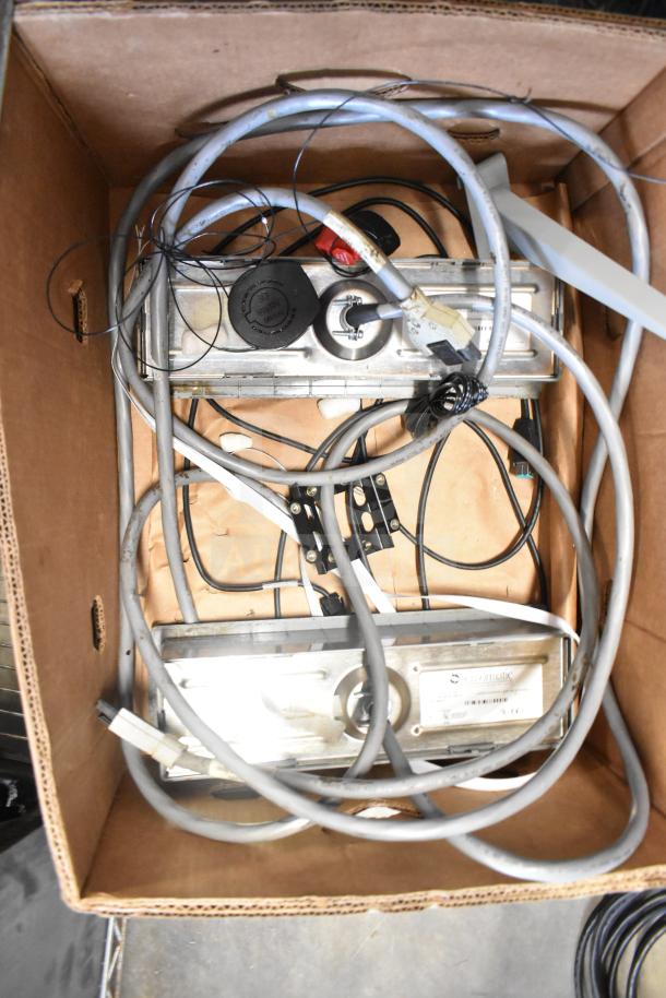 Lot of various items in a box, including cables and a Sensormatic ZBSTPSP-L device. Mixed condition, visible wiring.