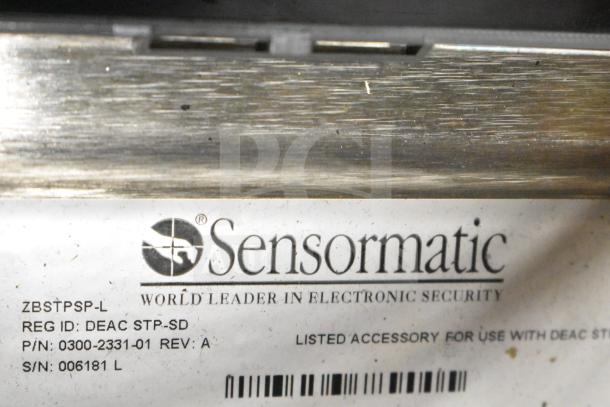 Sensormatic ZBSTPSP-L electronic security part, label shows model and serial numbers, part of auction lot with cables.