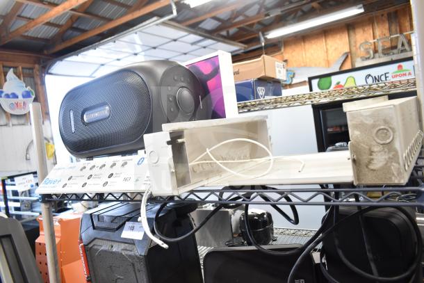 "Rave+ store display with electronic unit, black speaker, industrial setting, metal shelves, wires visible."