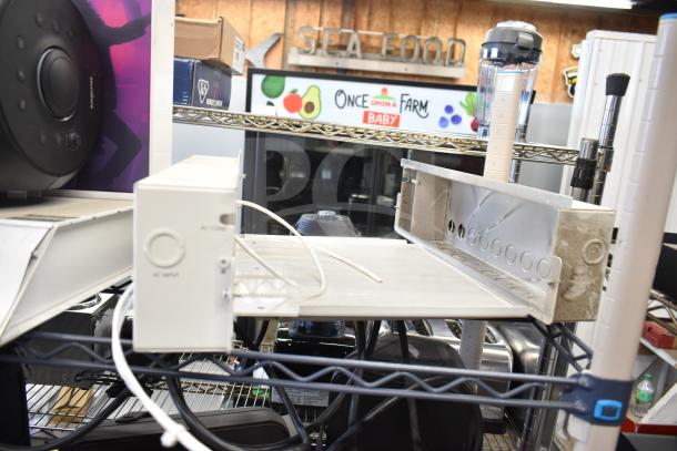 Store display and two electronic units on a shelf; includes AC input panel and marked display, showing wear, cords visible.