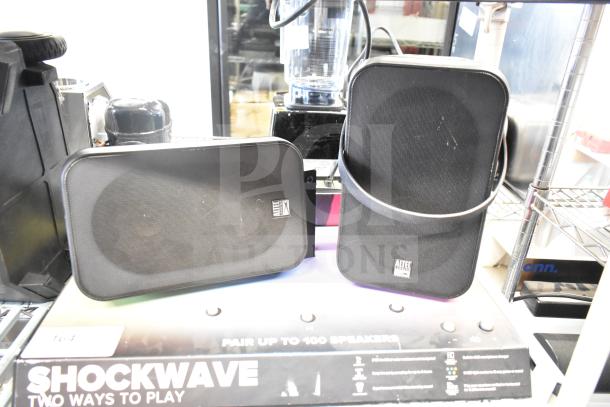 Shockwave store display featuring two Altec Lansing speakers in good condition, showcasing branding and function.