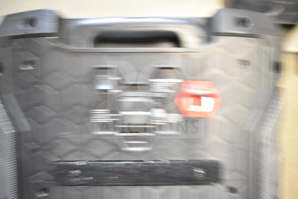 Blurry image of a Monster speaker with visible handle and control panel; no clear details or markings visible.