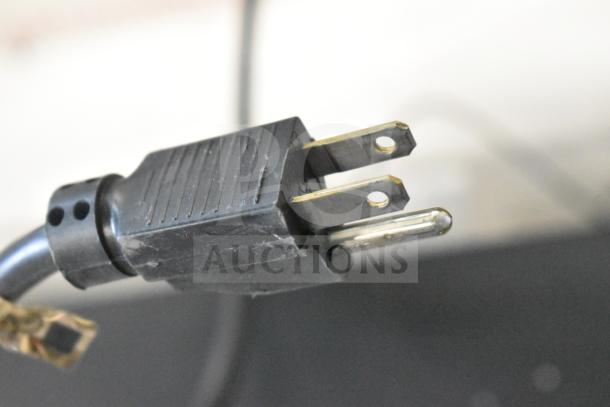 Close-up of a black electrical plug connected to the LG store display sound system.