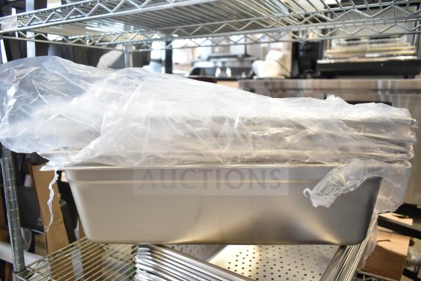 15 brand new scratch and dent drop-in bins stacked with protective wrap on a metal shelf.