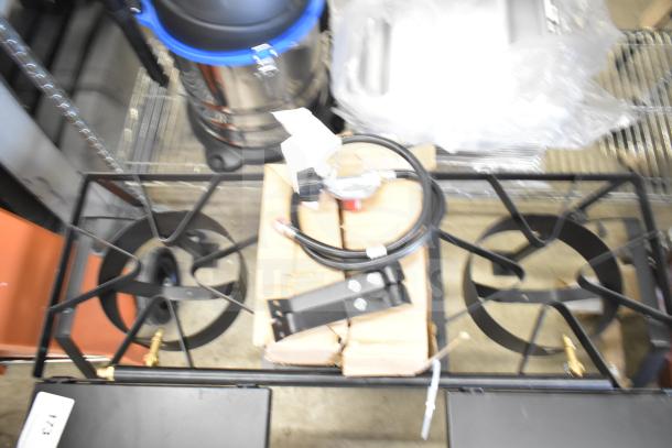 Brand new 2 burner propane gas range with visible scratches and dents. Includes attached gas hose and regulator.