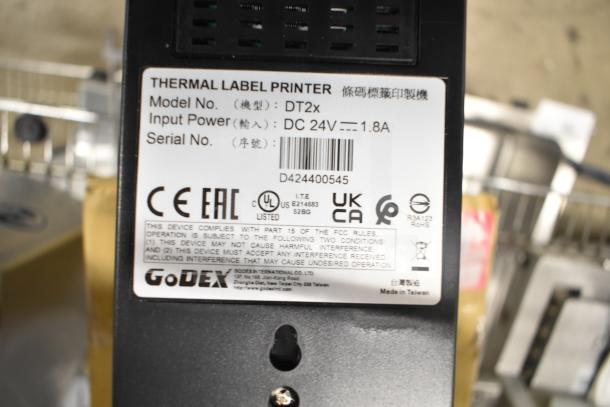 Brand new GoDex DT2x thermal label printer, scratch and dent model, with visible labels showing model, input power, and certifications.