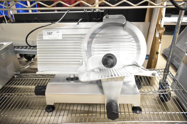 Globe Chefmate C12 meat slicer, new with scratches, features blade sharpener. 115 Volts, 1 Phase. Auction tag visible.