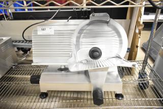 Globe Chefmate C12 meat slicer, new with scratches, features blade sharpener. 115 Volts, 1 Phase. Auction tag visible.