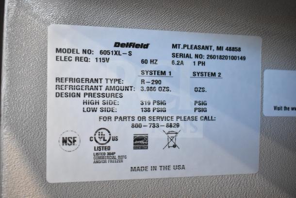 Label on a new Delfield 6051XL-S commercial cooler, showing model, 115V, refrigerant type R-290, and pressure details.