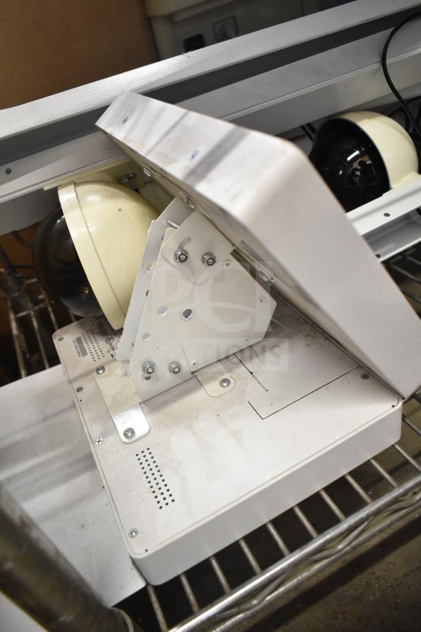 Security system setup featuring two monitors and dome cameras, mounted on a metal frame, in used condition.