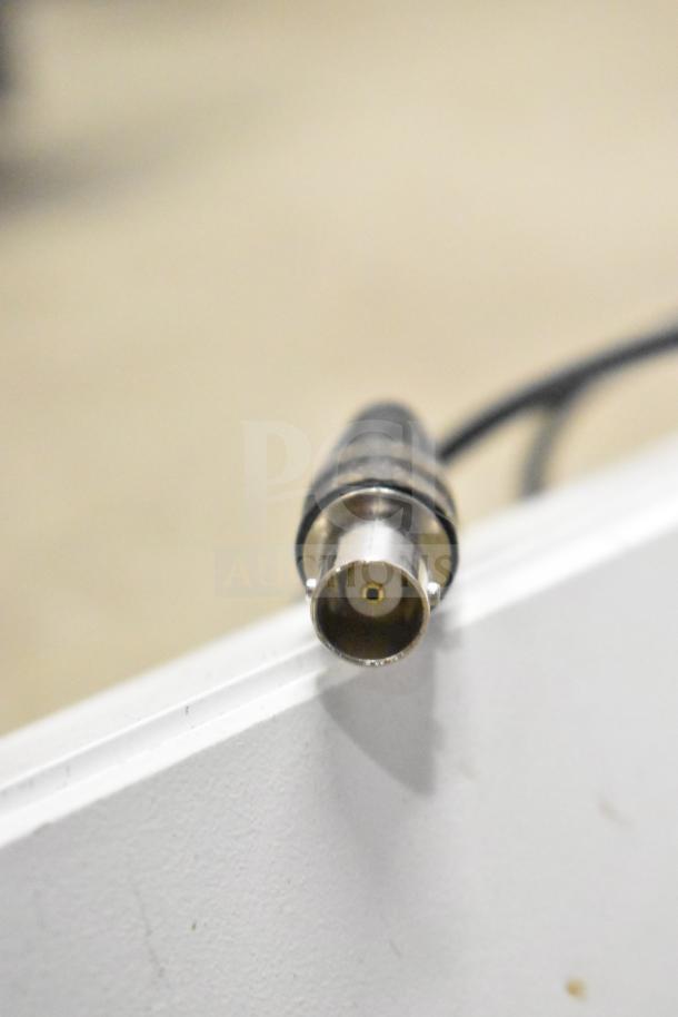 Close-up of a coaxial cable connector for a security system set up with 2 monitors and cameras.