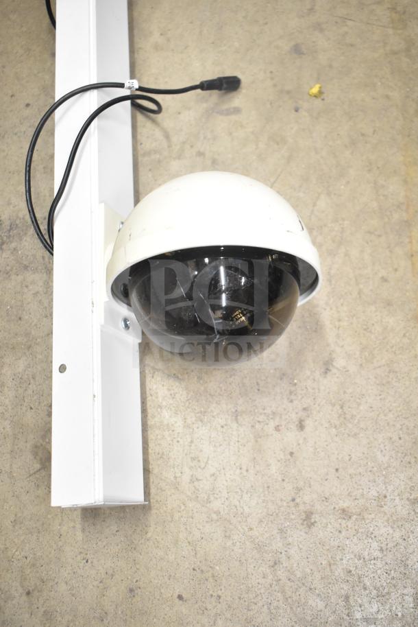 Security camera with a black dome, mounted on a white bracket. Wires connected. Part of a full security system set.