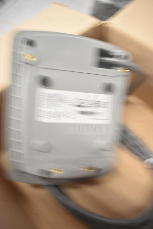 Blurry image of a Sensormatic ZBSMPCPEF Compact Pad Pro with cables in a cardboard box. Condition unclear.