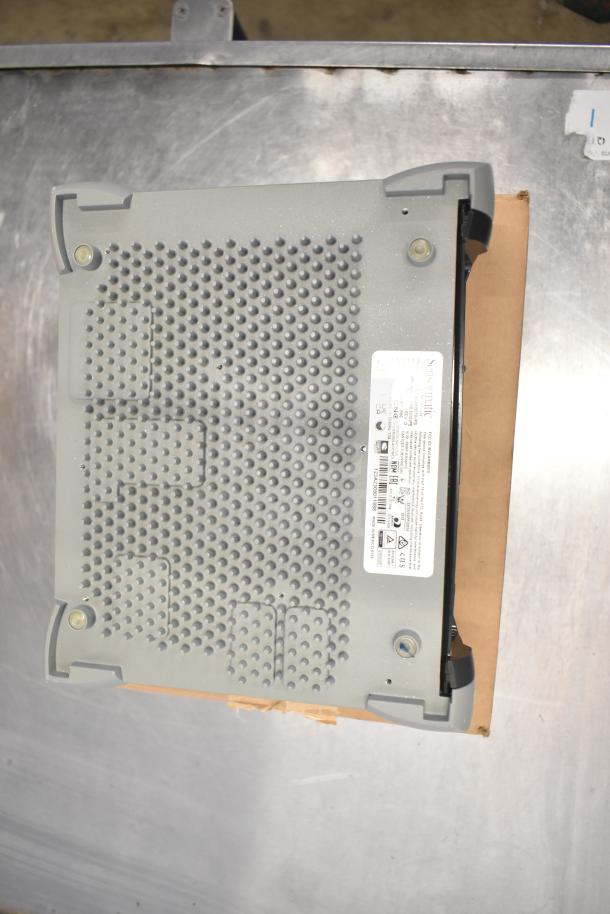 Sensormatic ZBSMPCPEF Compact Pad Pro on metal surface, features textured bottom and visible label details, gray color.