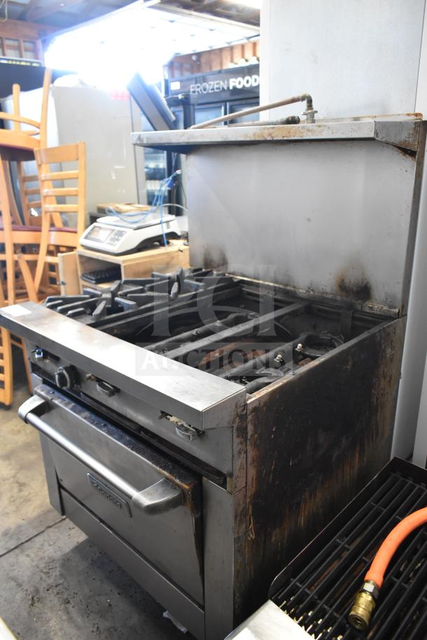 Garland commercial 6 burner range with oven, over shelf, and backsplash. Shows signs of wear, suitable for high-volume use.