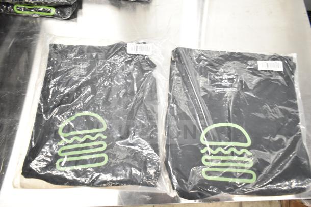 Seven new Shack Staff Tees, sizes XL, MD, 2XL, in packaging. Visible burger logo and barcode on plastic.