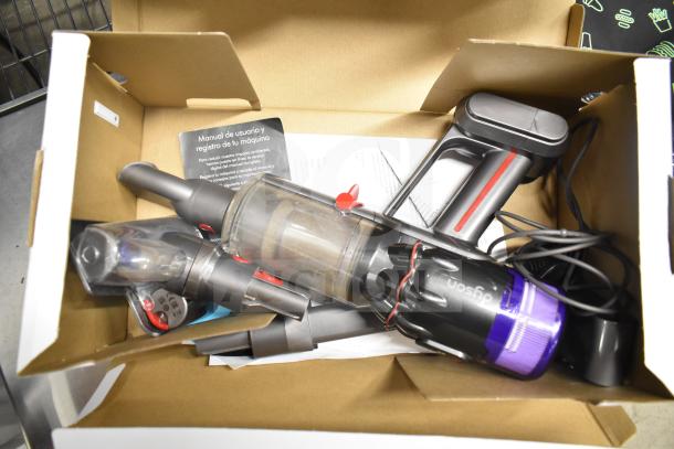 Dyson Humdinger vacuum cleaner in open box with attachments and user manual, appears lightly used.