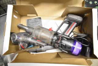 Dyson Humdinger vacuum cleaner in open box with attachments and user manual, appears lightly used.