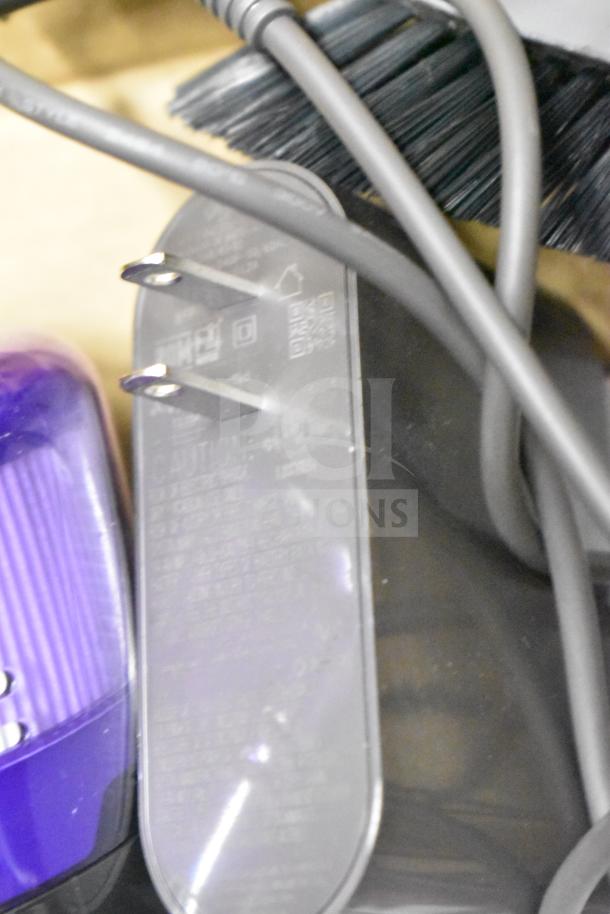 Dyson Humdinger Vacuum Cleaner in good condition, features power cord with plug and visible labeling on charger.