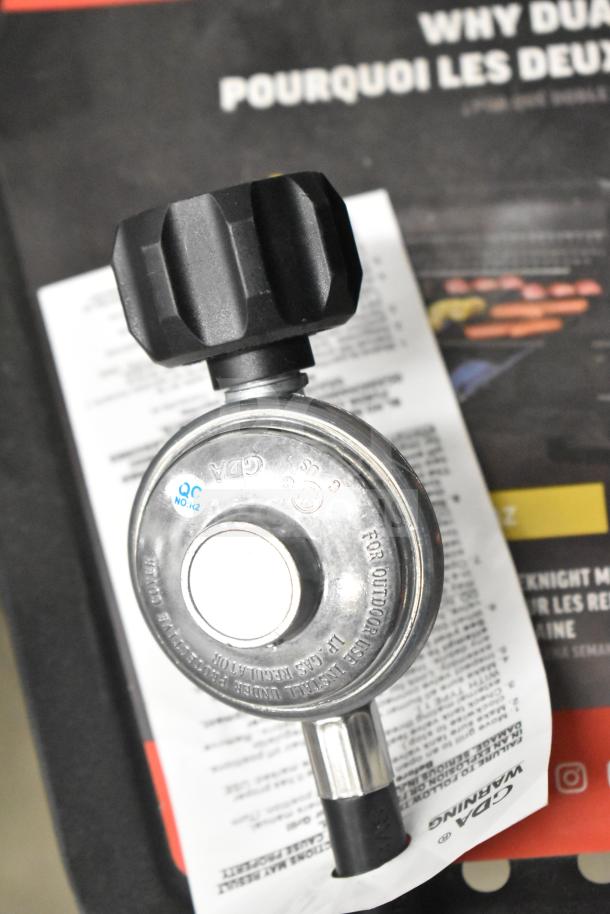 Char-Griller CG30282925 FlexFuel combo grill regulator detail, showing QC label and outdoor use instructions on packaging.