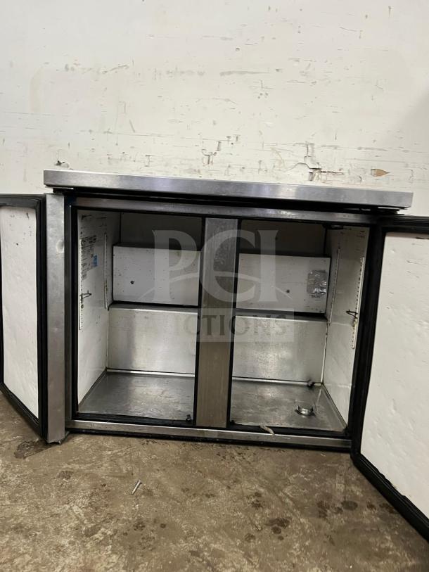 True TUC-36 undercounter cooler, stainless steel, 2-door, used, interior shelves, visible wear, model and brand labels inside.