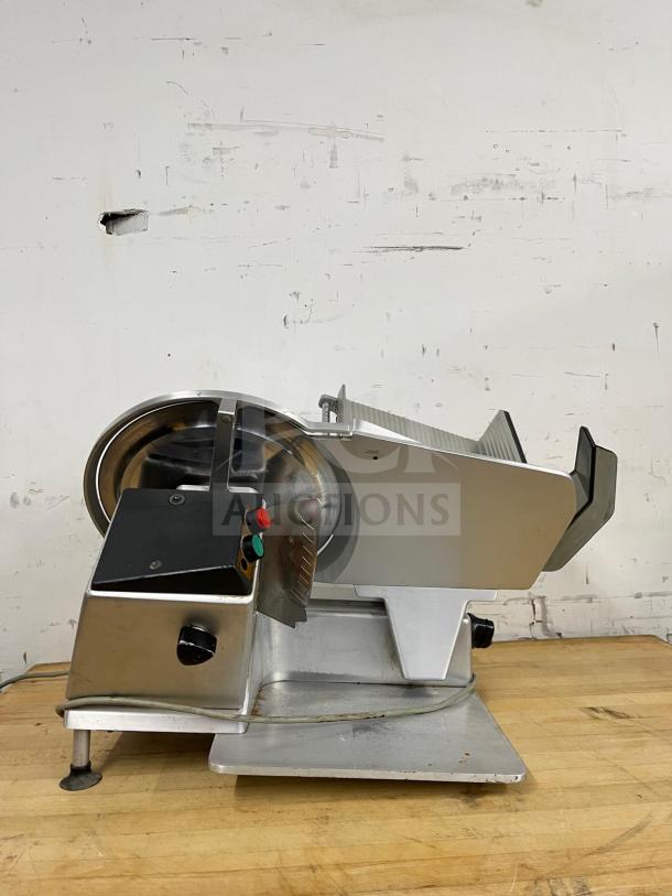 Steel manual food slicer with a robust build, featuring a shiny blade and adjustable thickness control, in used condition.