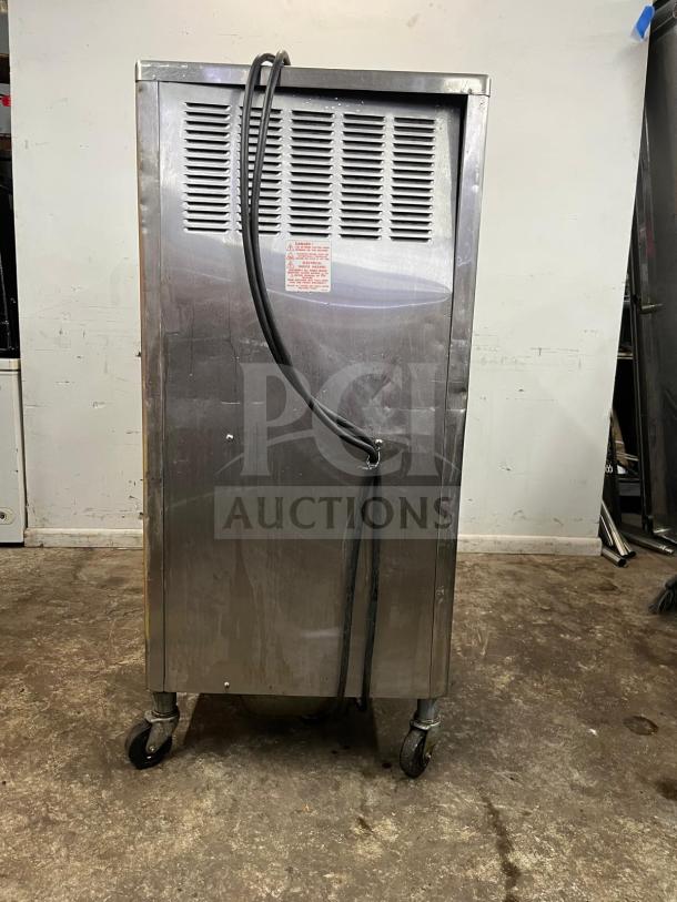 Taylor 342D double flavor frozen drink machine, stainless steel, on casters, used condition, cables attached, rear view.