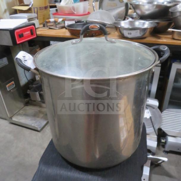 Stainless steel Tramontina 22-quart stock pot with lid, featuring sturdy handles, in good condition for auction.