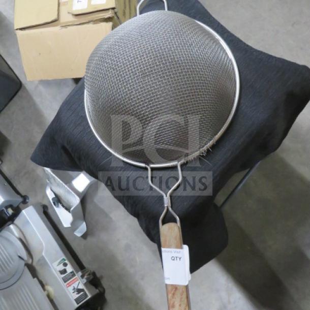 Mesh strainer with metal frame, wooden handle, and fine mesh netting. Tag reads "QTY." Appears in good condition.