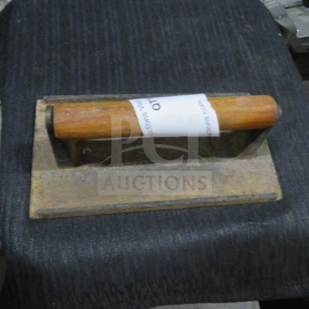 Heavy-duty steak weight with wooden handle, metal base. Used condition, slight wear. Tag visible indicating auction ID.