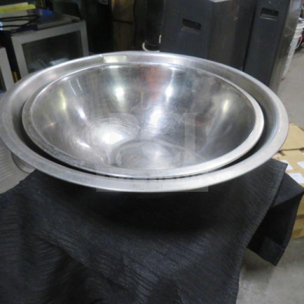 Assorted size stainless steel mixing bowls, slightly used, reflective surface, nested for compact storage.