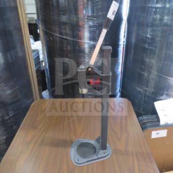 One bottle capper with hand lever on a wooden table, metal construction, used condition, ideal for home brewing.