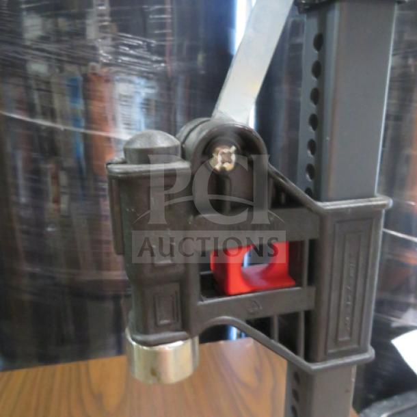 Metallic bottle capper with lever mechanism, adjustable height, and secure grip. Appears in good condition.