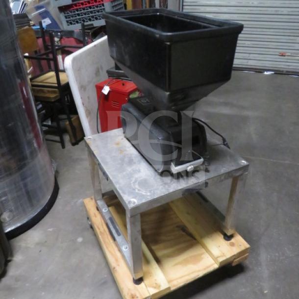Industrial hopper and motor on a metal and wood stand. Used condition with visible wear. No visible markings or labels.