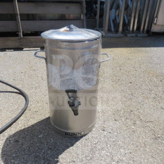 Bunn stainless steel satellite with lid, visible wear, side handles, and spout; brand label on the bottom front.