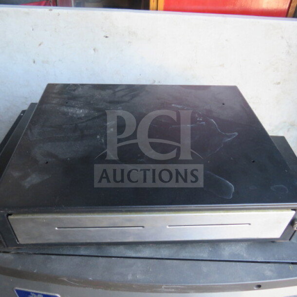 Black cash drawer with metal front panel, lightly used, visible scratches on top, standard size.