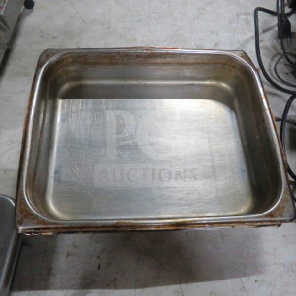 1/2 size 2.5-inch hotel pan with visible wear, scratches, and rust on edges; durable stainless steel construction.