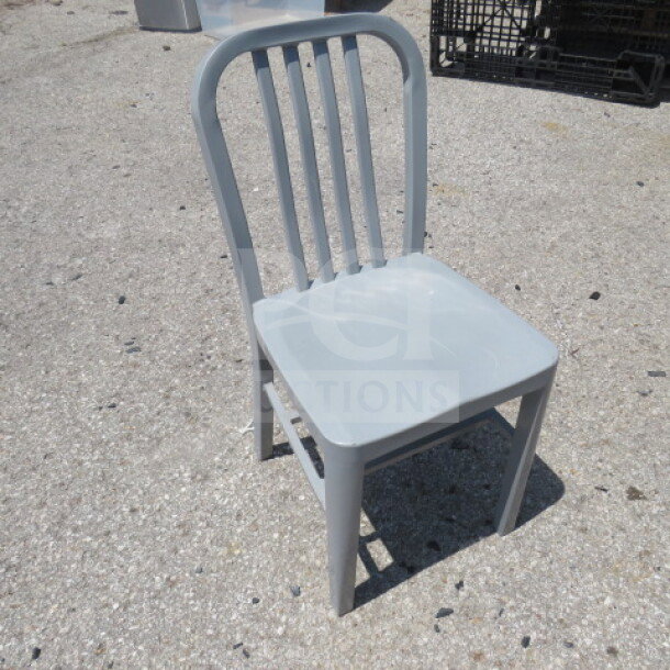 Silver metal indoor/outdoor chair with slatted back, sturdy design, and minor wear, suitable for versatile seating.