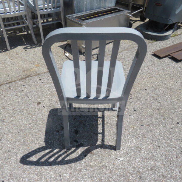 Silver metal indoor/outdoor chair, slatted back design, sturdy condition, suitable for versatile use.