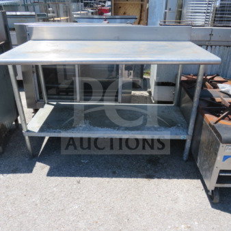 Stainless steel table with under shelf, used condition, visible wear marks, durable for kitchen or industrial use.